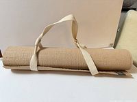 Rolled beige yoga mat with attached carry strap