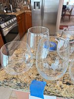 Group of four stemless wine glasses; two show white Texas outline design, two plain