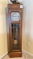 Full front view of oak grandfather clock showing entire case and glass lower door