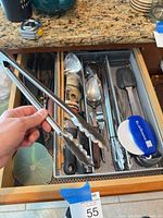 Drawer overview with assorted utensils and tongs held in hand