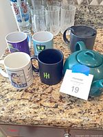 Group shot of all mugs, two teapots and six tall glasses