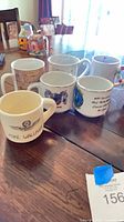 Six assorted ceramic mugs on table