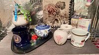 Group view of teapot, mugs, vase, teacup, saucer, tray