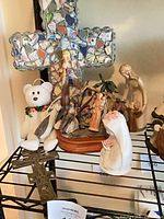 Overall view showing mosaic cross, plush bear, nativity set, ceramic Virgin, metal cross
