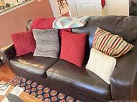 Front view of black leather sofa with pillows and throws