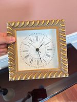 Front view of square gold-tone frame clock showing dial