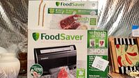 Stacked boxes showing FoodSaver 3400 vacuum sealer and separate box of bags/rolls