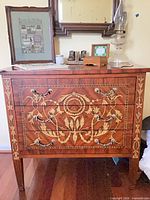 Front view of dresser showing all three drawers, inlay pattern, brass handles and part of wall mirror above