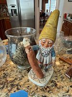 Gnome figurine beside painted glass candle holder showing scale and detail