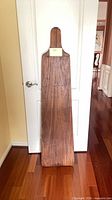Full view of the 60-inch wooden paddle leaning against door
