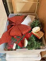 Top view of bin with red bow, greenery, fabric, lights
