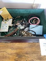 Overview of open box showing mixed jewelry pieces and booklets