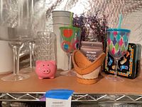 Entire lot on shelf showing hurricanes, tumblers, piggy bank, leather basket, tins, foil sprays