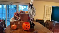 Overview showing jack-o-lantern pail, ceramic pumpkin jar, fabric ghost, basket with faux arrangement on wine crate