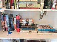 Shelf view showing standing hardcovers, stacked field guides and large nature volume