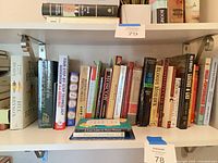 Shelf with assortment of hardcovers and paperbacks showing majority of titles