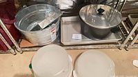 All items on shelf: bucket, stock pot on metal tray, plastic covers