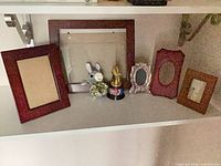 Group shot shows all frames, trophy, plush and pom on shelf