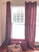 Curtain panels hung on rod with pillows at base