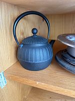 Cast iron teapot with lid and handle on shelf