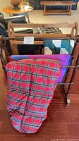 Front view showing dark spindle rack, red tartan, purple, and teal blankets