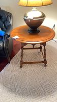 Overall view of round cherry side table next to chair