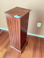 Closed view of slim mahogany media tower showing vertical grooves and pedestal base