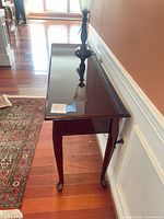 Angled side view showing tabletop gloss and cabriole legs