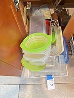 stack of clear Tupperware containers with green lids visible