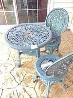 Round turquoise cast aluminum table with two matching chairs