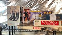 Overall lot on shelving showing game boxes, nutcracker, skate box