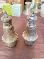 Front view of both tarnished sterling silver shakers showing overall form and wear