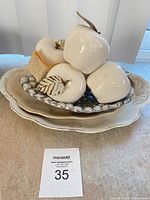 Stacked display of ceramic platters, silver-tone bowl and white apple ornaments