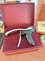 Lever-style corkscrew seated in red flocked interior box