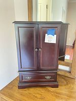 Front view of closed jewelry armoire showing doors and lower drawer