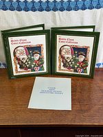 Two green Santa Claus Cover Collection binders and miniature sheet envelope displayed