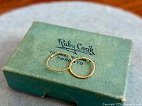 Twisted and plain 10K gold small hoop earrings on Ruby Cook Toronto box