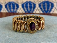 Full view of expansion bracelet showing purple glass centerpiece and link pattern