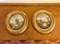 Two oval reverse paintings in gilt frames on wooden surface