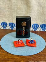 front view of dolls on cushions with lacquered box