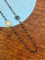 close-up of black spinel bead chain and two bezel-set sapphires