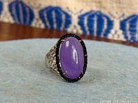 Front view of ring showing purple cabochon and black halo