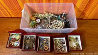 Overall lot showing plastic bin filled with jewelry and five open wood boxes