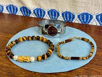 All three items: tiger’s eye bead bracelet, link bracelet, silver tone cuff watch