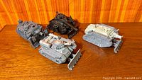 Four Warhammer 40K tanks on wooden surface