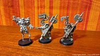 Front view of all three unpainted metal miniatures on bases