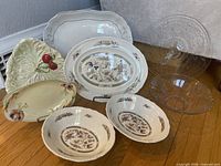 Group shot of two ironstone platters, two matching bowls, two leaf dishes, footed glass stand and etched glass bowl