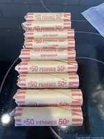 Nine paper coin rolls stamped 50 pennies 50¢ on stovetop