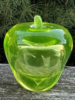 Front view of vaseline glass apple paperweight showing shape, color and stem