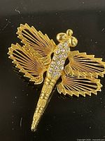 Front view of gold-tone dragonfly brooch with clear rhinestones